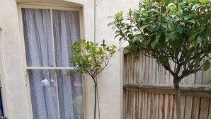 Eine Terrasse mit Holztisch und -stühlen, einem kleinen Baum und einem Holzzaun.