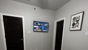 Een slaapkamer met twee bedden, een flatscreen televisie aan de muur en een plafondventilator.