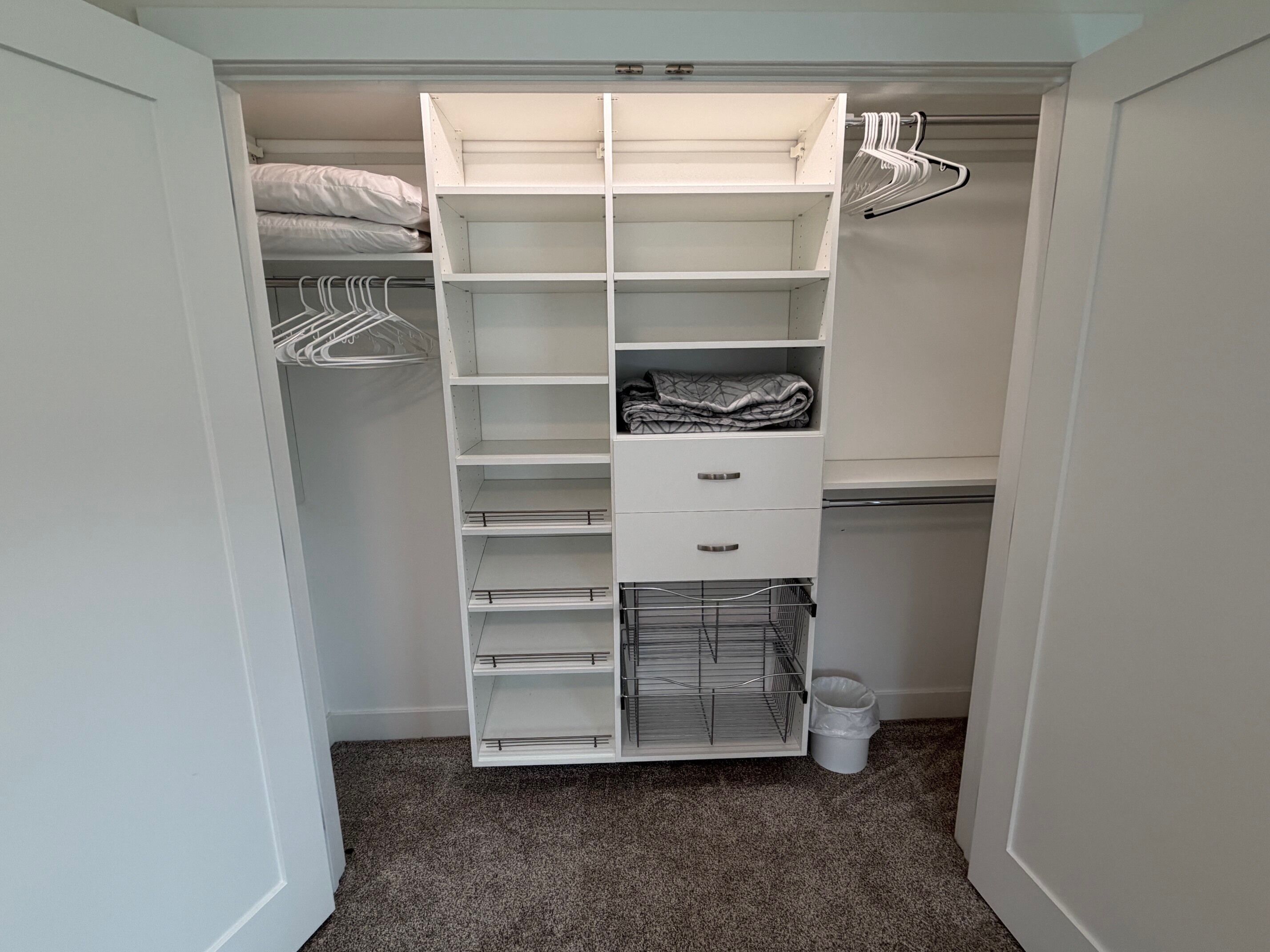 A walk-in closet with open shelves, hanging space, and drawers.