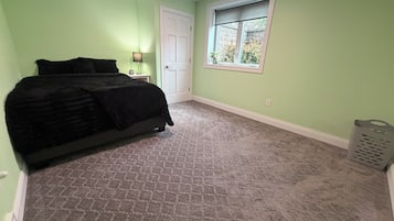 Een slaapkamer met een bed, nachtkastje, raam en deur.