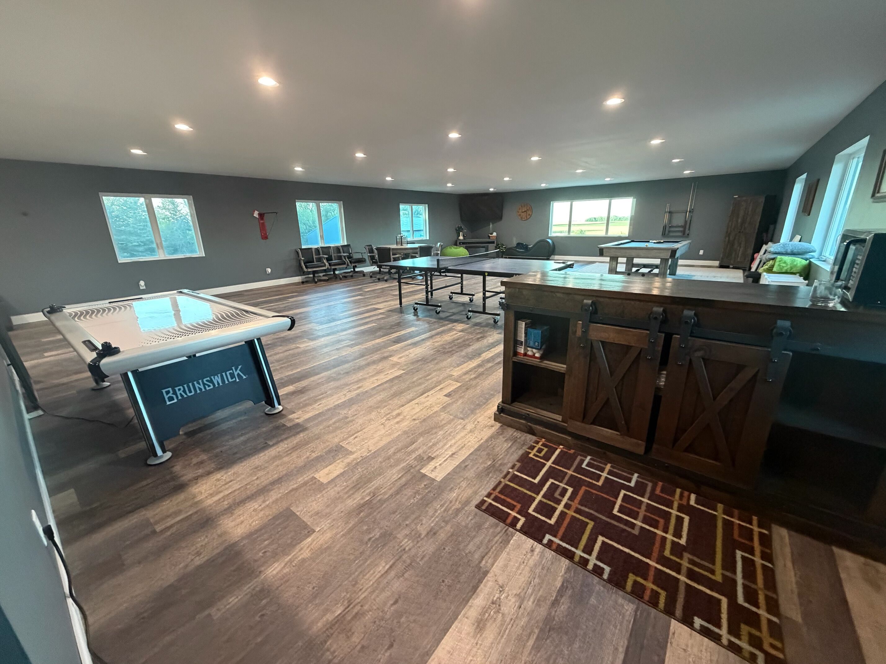 A spacious indoor area with a pool table, seating, and a kitchenette.