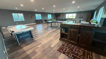 A spacious indoor area with a pool table, seating, and a kitchenette.
