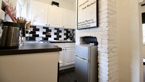 A modern kitchen with white cabinets, a stainless steel Bosch coffee maker, and a black and white checkered backsplash.