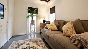 A living room with a sofa, a lamp, a plant, and a rug.