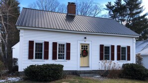 A white house with a yellow door, numbered 20, and red shutters. - Rivers Edge (Freedom)