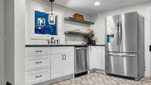 A modern kitchen with white cabinets, a stainless steel refrigerator, and a patterned floor. - Rivers Edge (Freedom)