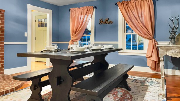 A dining area with a table set for four, a bench, and a decorative wall sign. - Rivers Edge (Freedom)