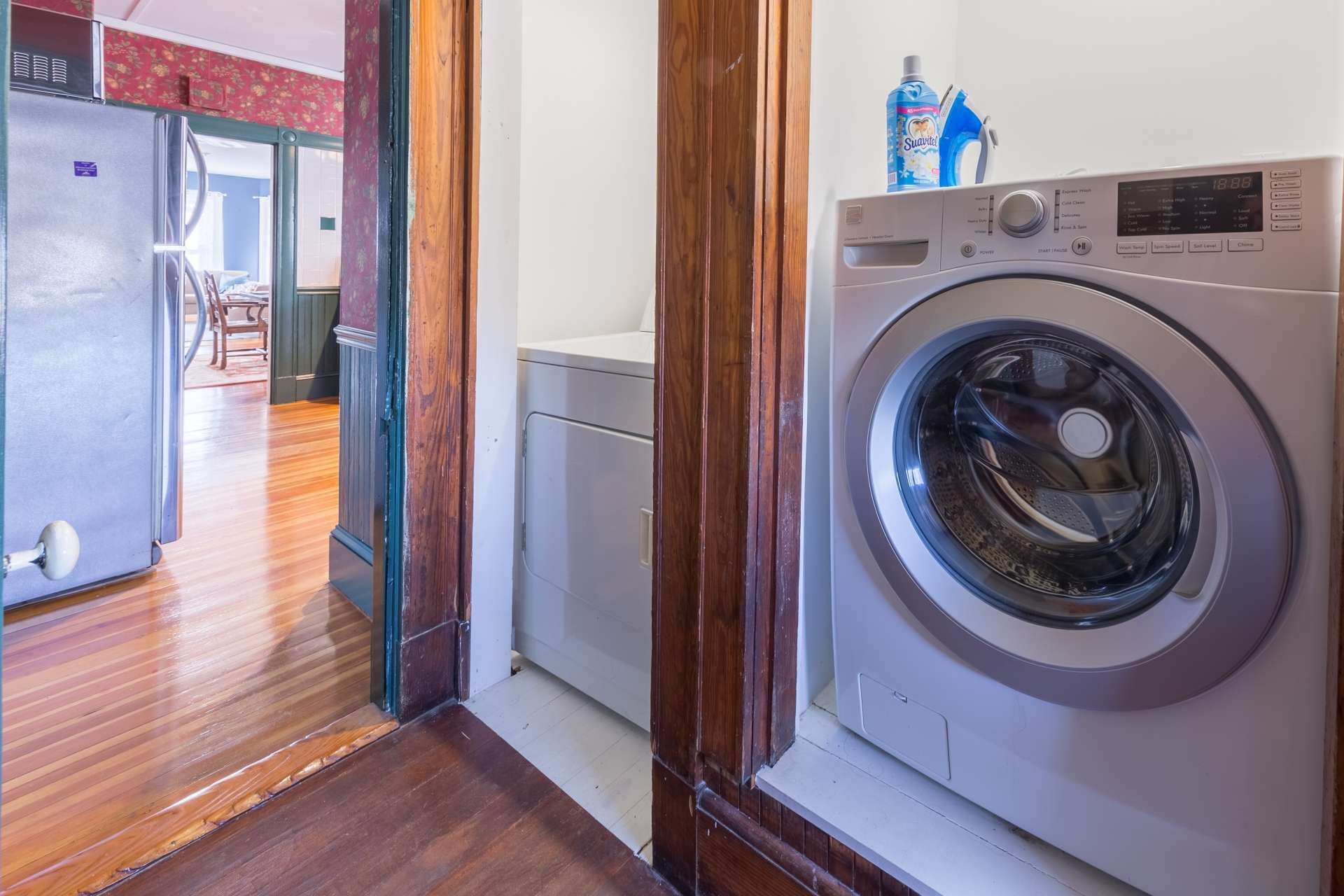 Une buanderie équipée d’un lave-linge à chargement frontal, d’un réfrigérateur et d’un petit meuble de rangement.
