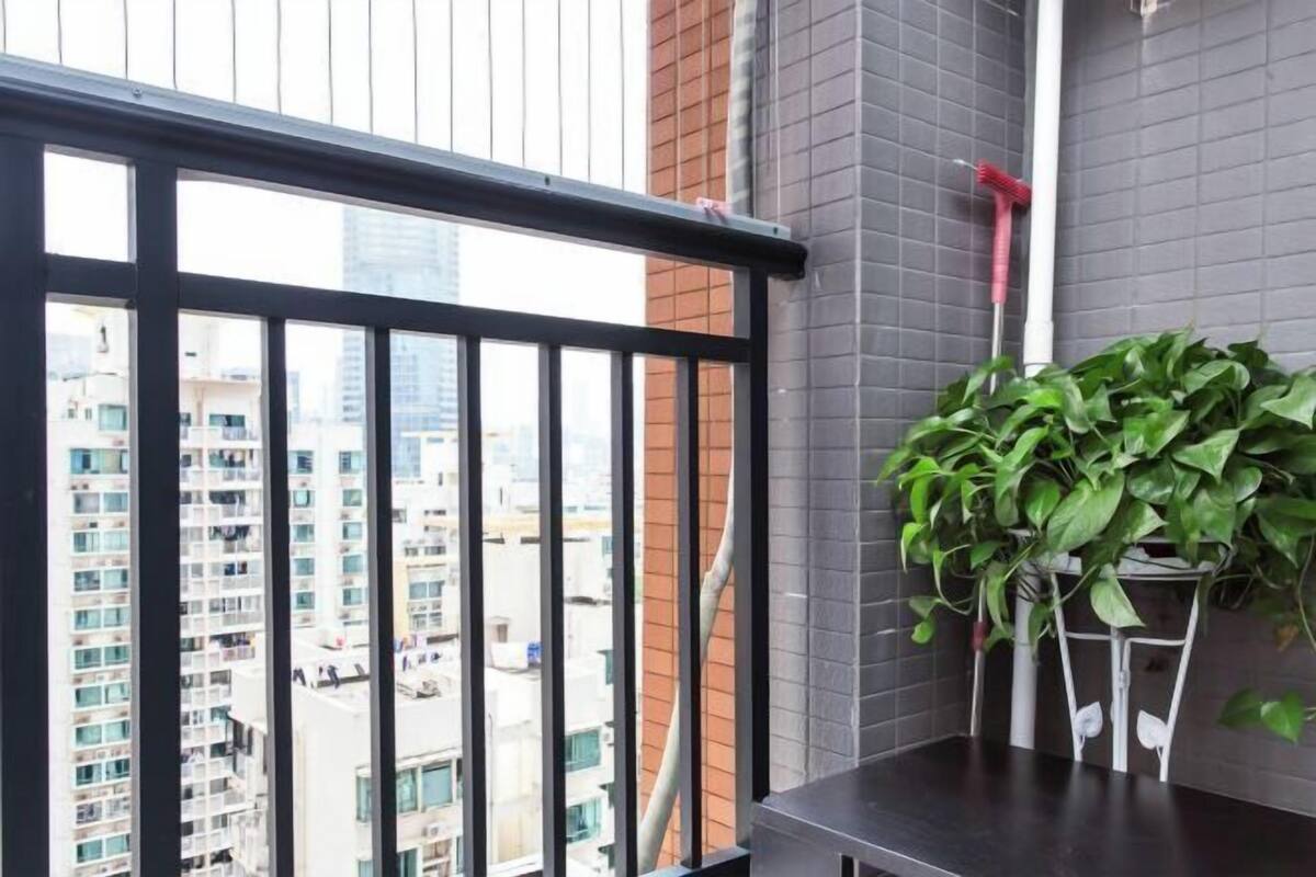 A balcony with a view of a cityscape, a potted plant, and a red cleaning tool.