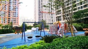 A playground with swings and climbing structures, surrounded by greenery and tall buildings. - Lian'Jia Apartment Hotel (Shenzhen Dachong Xincheng Huayuan) (Shenzhen)