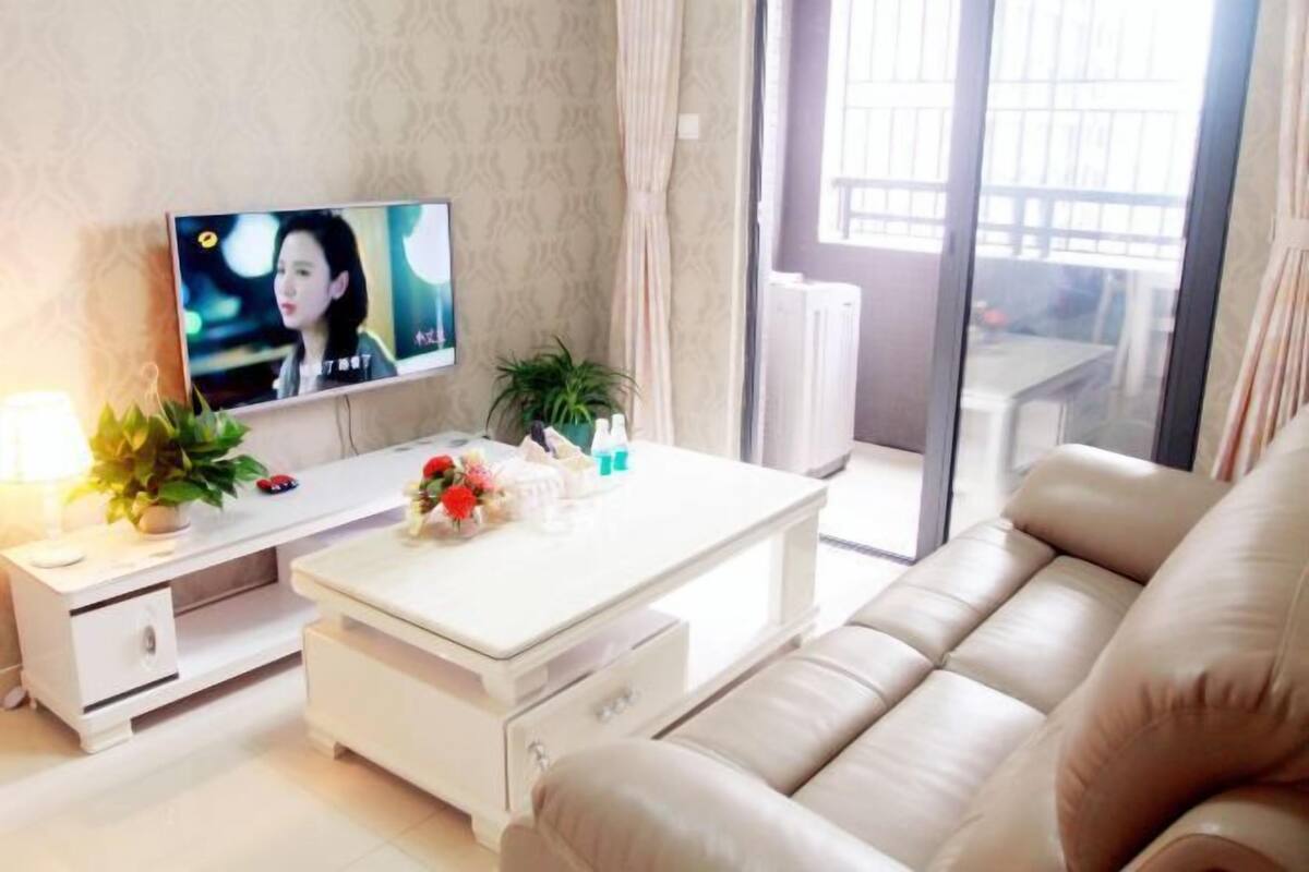 A living room with a sofa, a coffee table, a TV, and a plant.