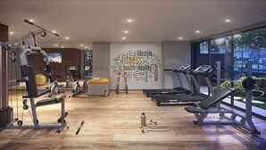 Une salle de sport moderne équipée de machines de cardio, d’appareils de musculation et d’un mur orné de mots liés à la santé.