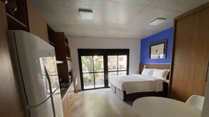 Une chambre d’hôtel comprenant un lit, une table à manger, un réfrigérateur et un coin cuisine.