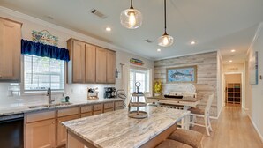 A modern kitchen with wooden cabinets, a marble island, pendant lighting, and a view of the dining area. - Resort Home ~ 1 Mi to Myrtle Beach Access! (Myrtle Beach)