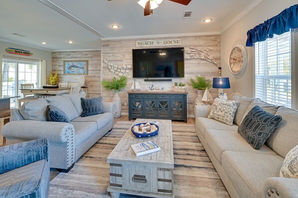 A modern living room with a large TV, wooden accent wall, and a 'Beach House' sign. - Resort Home ~ 1 Mi to Myrtle Beach Access! (Myrtle Beach)