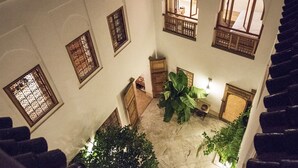 A high-ceilinged atrium with multiple arched windows, a central staircase, and a large potted plant. - Riad Rossi (Marrakech)
