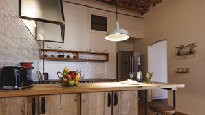 A kitchen with a wooden island, a stainless steel refrigerator, and a hanging light fixture. - Bravissimo Carrer Nou, cosy 2-bedroom apartment in the center of Girona (Girona)