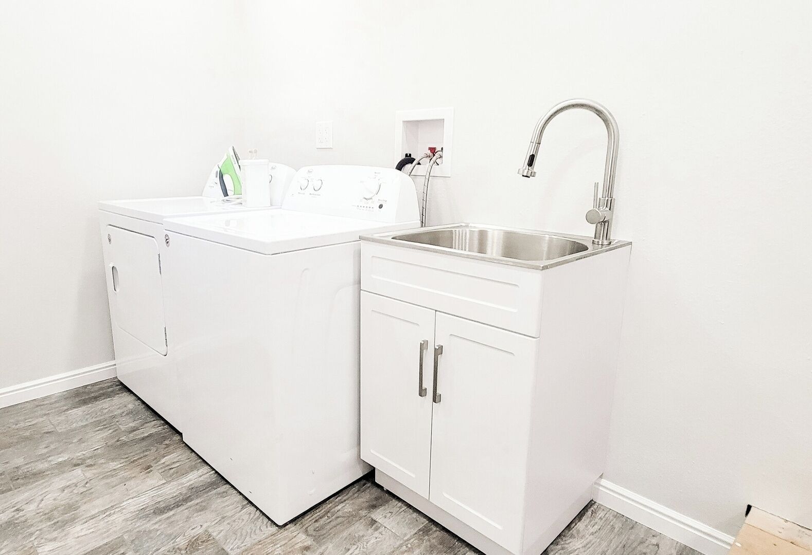 A laundry area with a washing machine, dryer, and a sink with a faucet.