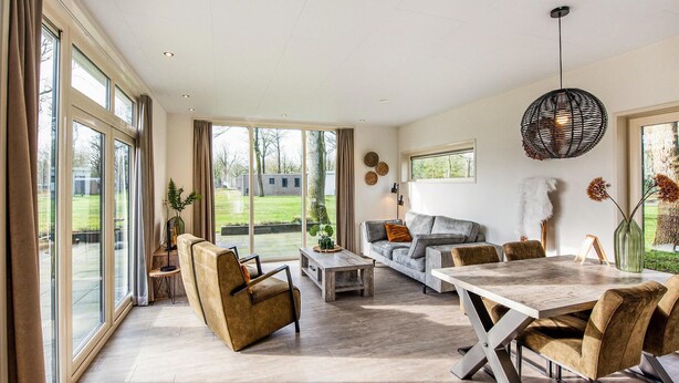 A spacious living room with a large window, a sofa, a coffee table, and a dining area with chairs. - 2 bedroom lovely home in Zorgvlied (Zorgvlied)