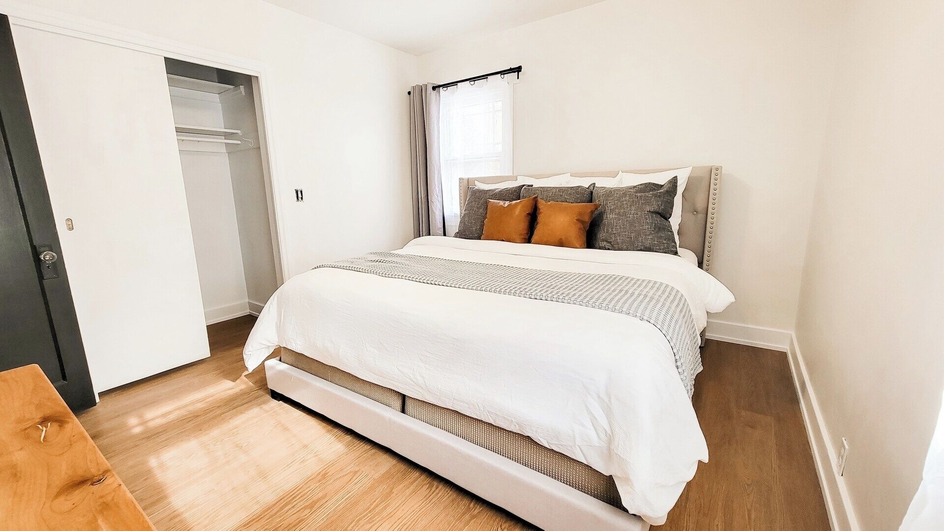 A bedroom with a bed, a wardrobe, and a window with curtains.