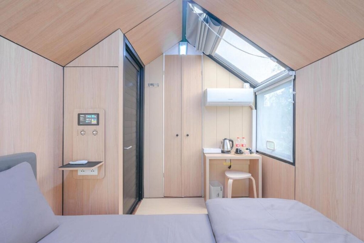 A compact room with a bed, a desk, and a kitchenette.