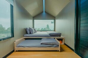 A compact bedroom with two beds, a large window, and a sloped ceiling. - Bobocabin Gunung Mas (Cisarua)