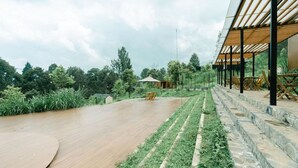 A spacious outdoor area with a wooden deck, stone steps, and a covered seating area. - Bobocabin Gunung Mas (Cisarua)