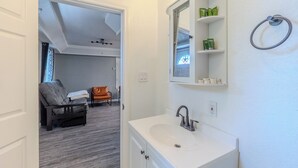 A bathroom with a white sink, mirror, and shelves with toiletries. - 2-Bedroom in the Heart of SA (San Antonio)