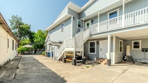 A residential building with a front porch, a staircase leading to the second floor, and a garage door. - 2-Bedroom in the Heart of SA (San Antonio)
