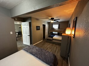 Une petite pièce avec un lit superposé, un ventilateur de plafond et une lampe fixée au mur.