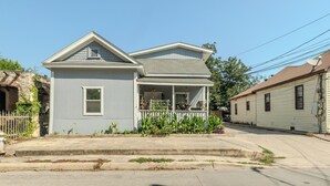 A two-story house with a front porch, a small attached garage, and a satellite dish. - 2-Bedroom in the Heart of SA (San Antonio)