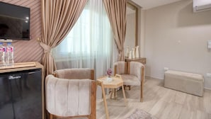 A modern hotel room with a flat-screen TV, a minibar, two armchairs, a small table, and a sofa. - Pyramids Sunrise Inn (Giza)