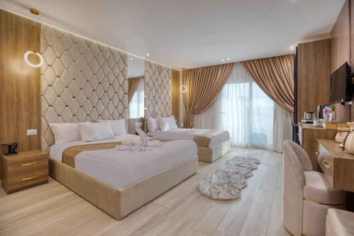 A modern hotel room with a large bed, a smaller bed, a desk, and a television.