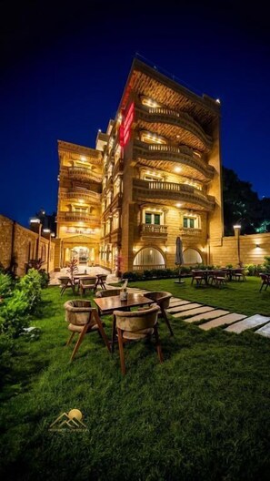 A multi-story hotel with outdoor seating and a well-lit facade.