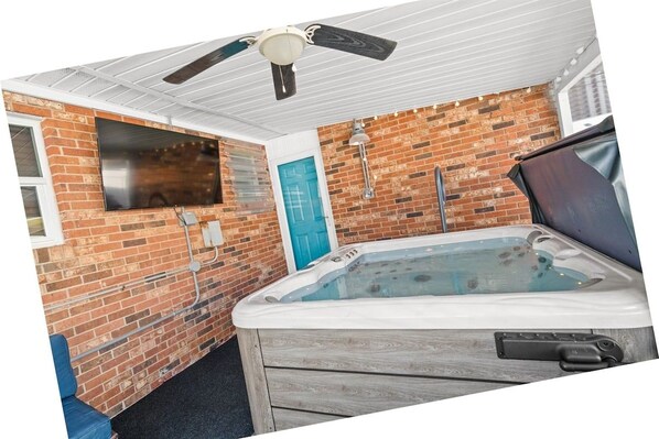 Ein Wellnessraum mit Whirlpool, Deckenventilator und Backsteinwand.
