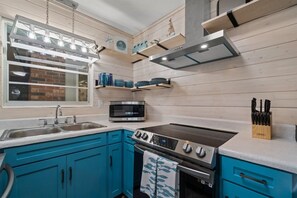 A kitchen with a stove, microwave, and sink.