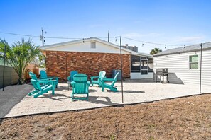 Un jardin avec un mur en briques, un patio couvert et un espace salon extérieur.