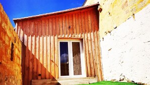 Un edificio de madera con puerta de cristal y un pequeño jardín delantero.