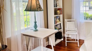 A room with a white table, a white chair, a bookshelf, and a lamp. - Historic Cozy Parkside Cottage in Savannah (Savannah)