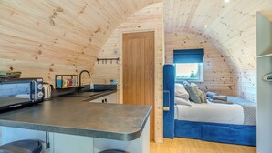 A compact, wooden interior with a kitchenette, a bed, and a small seating area. - Wood View - UK43707 (Scarborough)