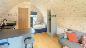 A cozy cabin interior with a kitchen, dining area, and a living room with a sofa and a bed. - Wood View - UK43707 (Scarborough)