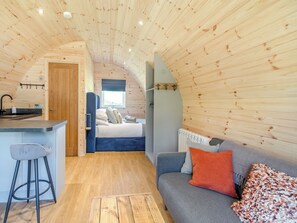 Un interior compacto de madera con kitchenette, una cama y una zona de estar.
