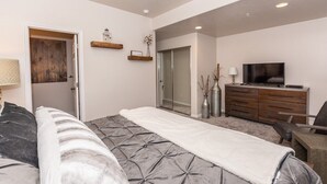 A bedroom with a bed, a dresser, a TV, and a door leading to another room. - Adventure Awaits at Mountain Hollow Retreat in Eden! (Eden)