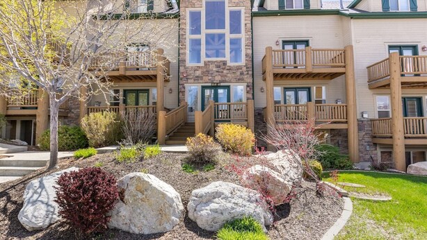 A multi-story building with a stone facade, wooden balconies, and a landscaped garden with rocks and shrubs. - Adventure Awaits at Mountain Hollow Retreat in Eden! (Eden)