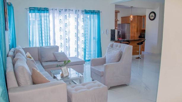 A modern living room with a sofa set, a coffee table, and a dining area with a kitchen in the background. - Puerto Plata House Full of Peace ❤️ (puerto plata)