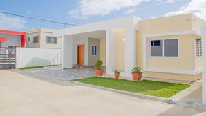 A modern two-story house with a flat roof, a front porch, and a small front yard with potted plants. - Puerto Plata House Full of Peace ❤️ (puerto plata)