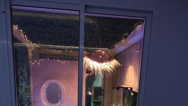 Ein moderner Außenbereich mit Terrasse, Whirlpool, Kamin und Lichterketten.