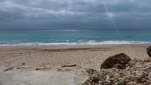 Ein Strand mit bewölktem Himmel und ruhiger See.
