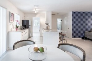 Enjoy cooking and dining in this spacious kitchen with a central island and bar stools, seamlessly connected to a dining area with a round table.