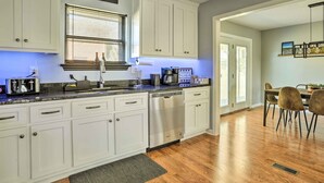 A modern kitchen with white cabinets, a dishwasher, and a dining area with a table and chairs.
